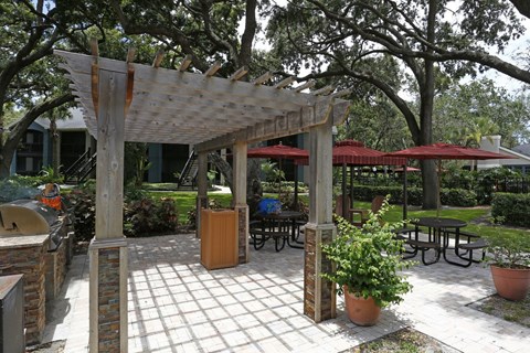 A wooden pergola with a tiled floor and potted plants.