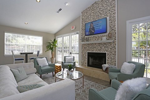 A living room with a stone fireplace and a flat screen TV mounted above it.