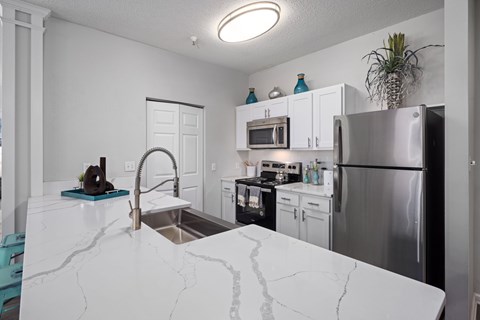 A kitchen with a marble counter top and stainless steel appliances.