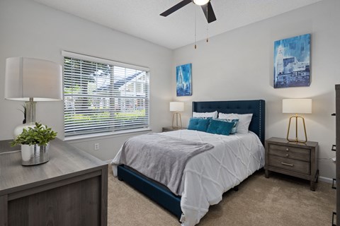 A bedroom with a bed, nightstand, and a ceiling fan.
