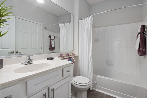 A white bathroom with a toilet, sink, and bathtub.