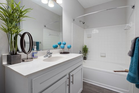 A white bathroom with a white sink and a white bathtub.