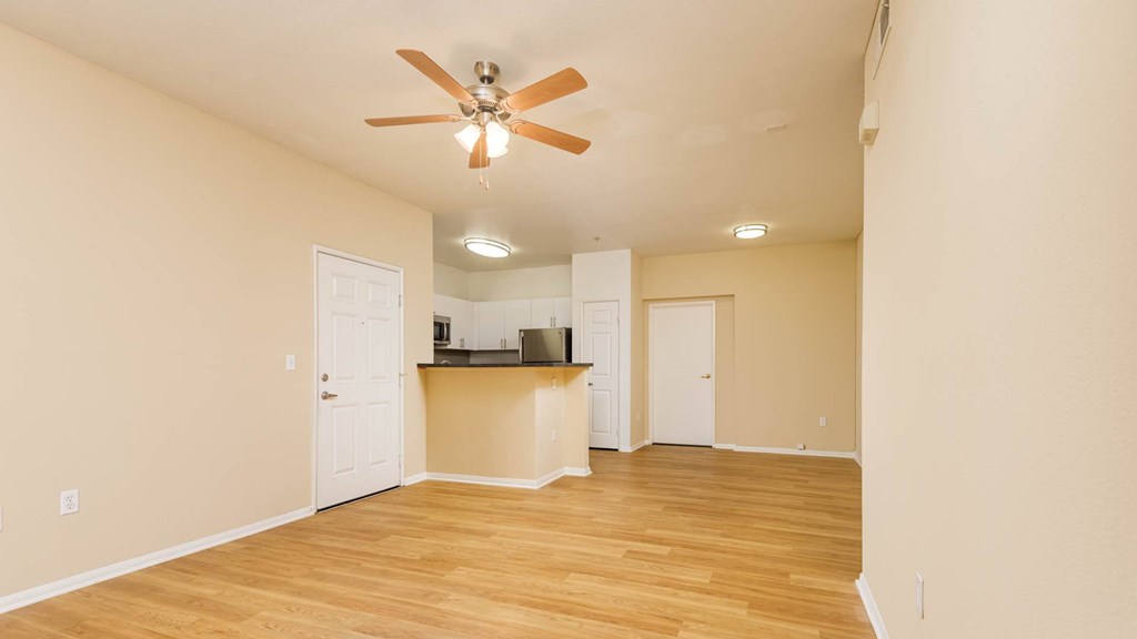 A room with a ceiling fan and wooden floors.
