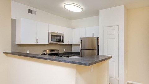 A kitchen with white cabinets and a stainless steel refrigerator.