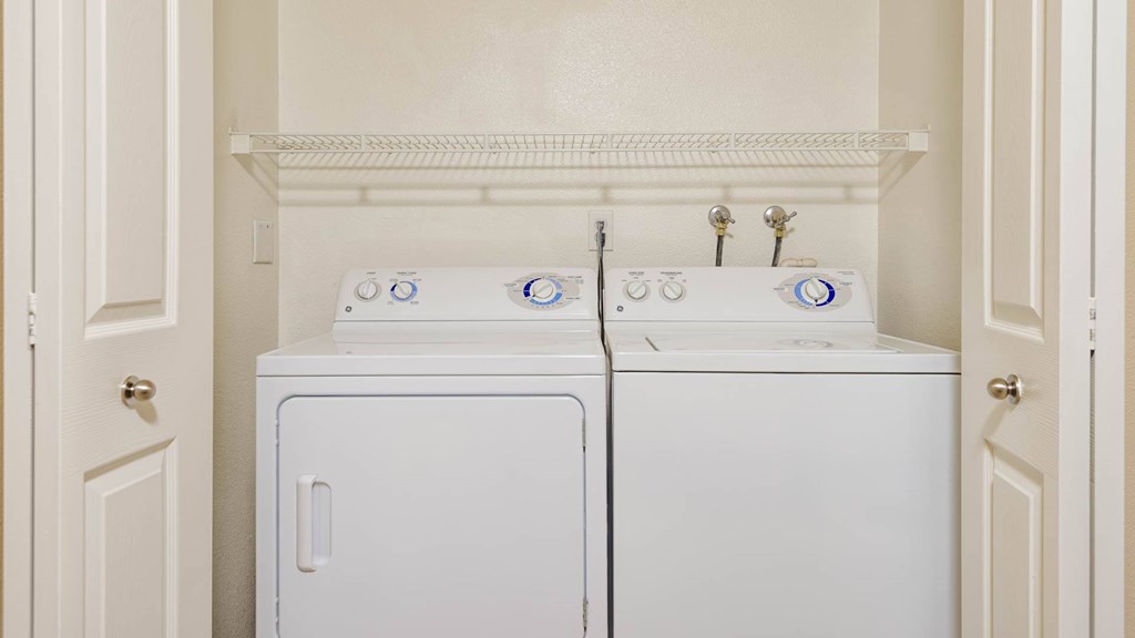 Two white front loading washing machines in a laundry room.