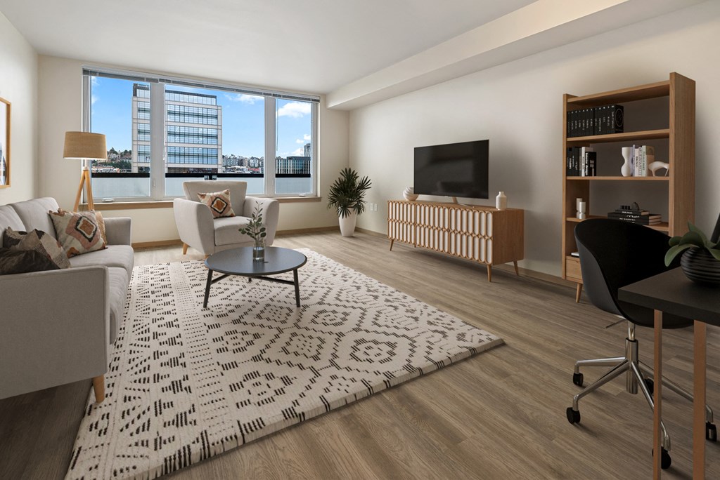 A living room with a white sofa, a black chair, a coffee table, a television, and a large window.