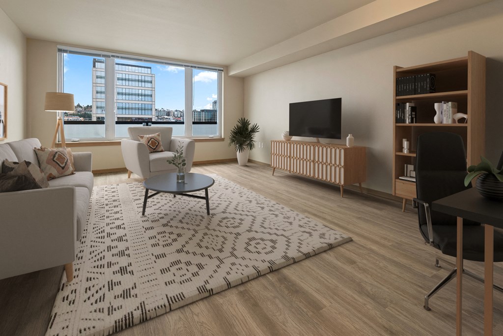 A living room with a white sofa, a black chair, a television, and a large window overlooking a cityscape.