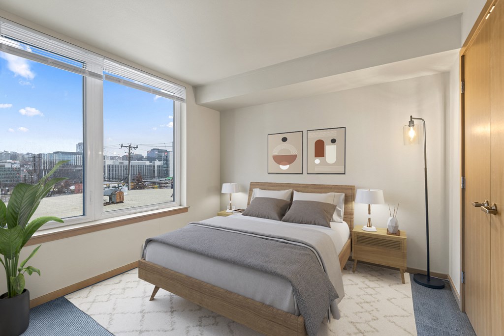 A bedroom with a large bed and a view of the city outside the window.