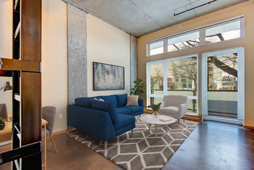A living room with a blue couch and a painting on the wall.