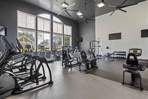 A gym with a variety of equipment including treadmills, stationary bikes, and weight machines.