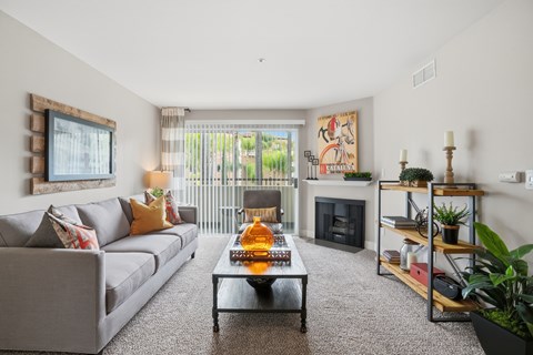 A living room with a grey couch, a coffee table, a fireplace, and a painting on the wall.