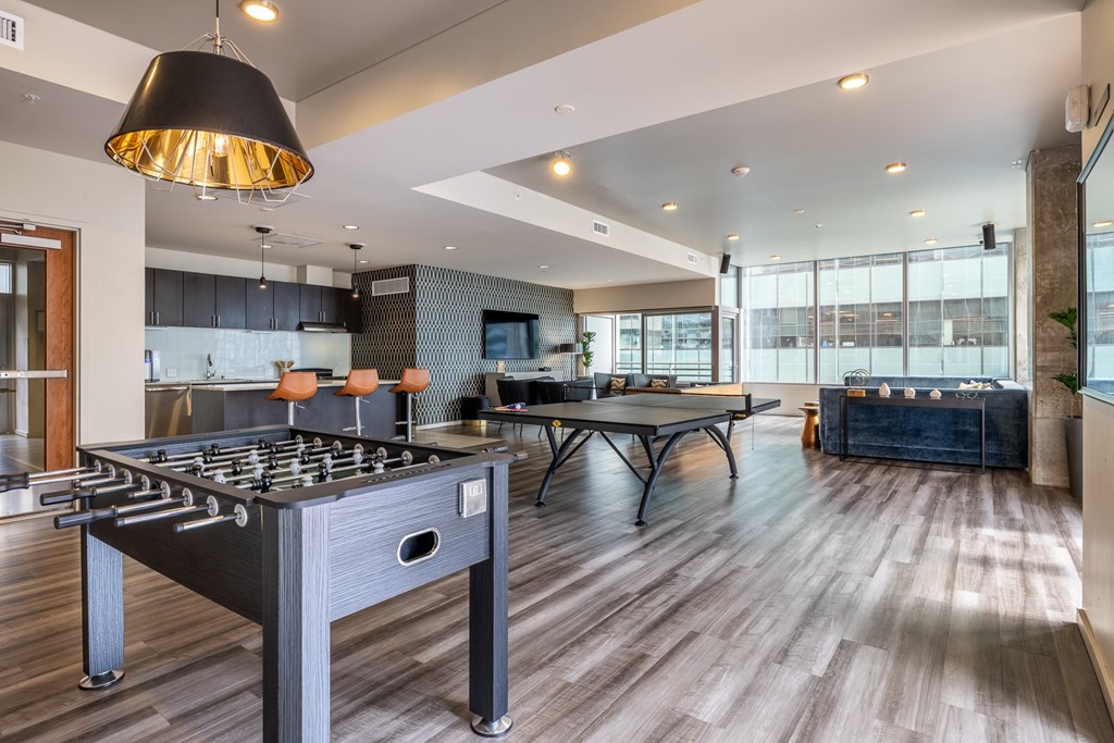 A foosball table is in the middle of a room with a ping pong table and a dining table.