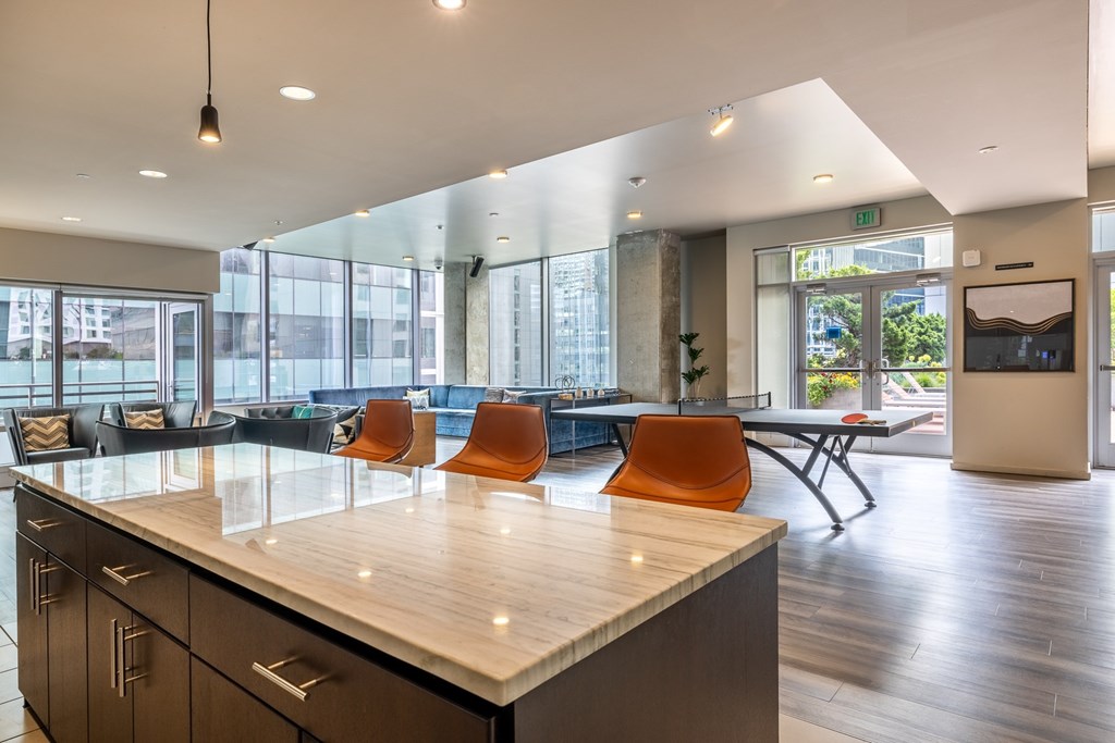 A modern kitchen with a long counter and orange chairs.