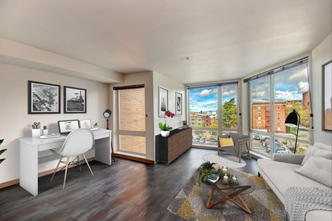 A modern living room with a white desk and a large window overlooking the city.