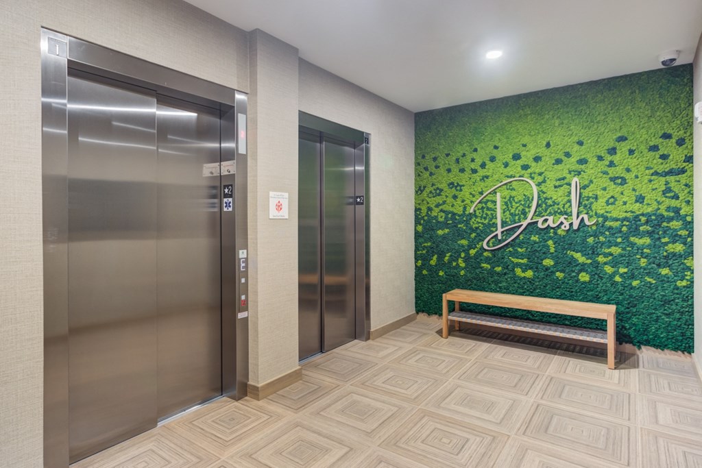 an elevator lobby with a green wall with the name of the company on it
