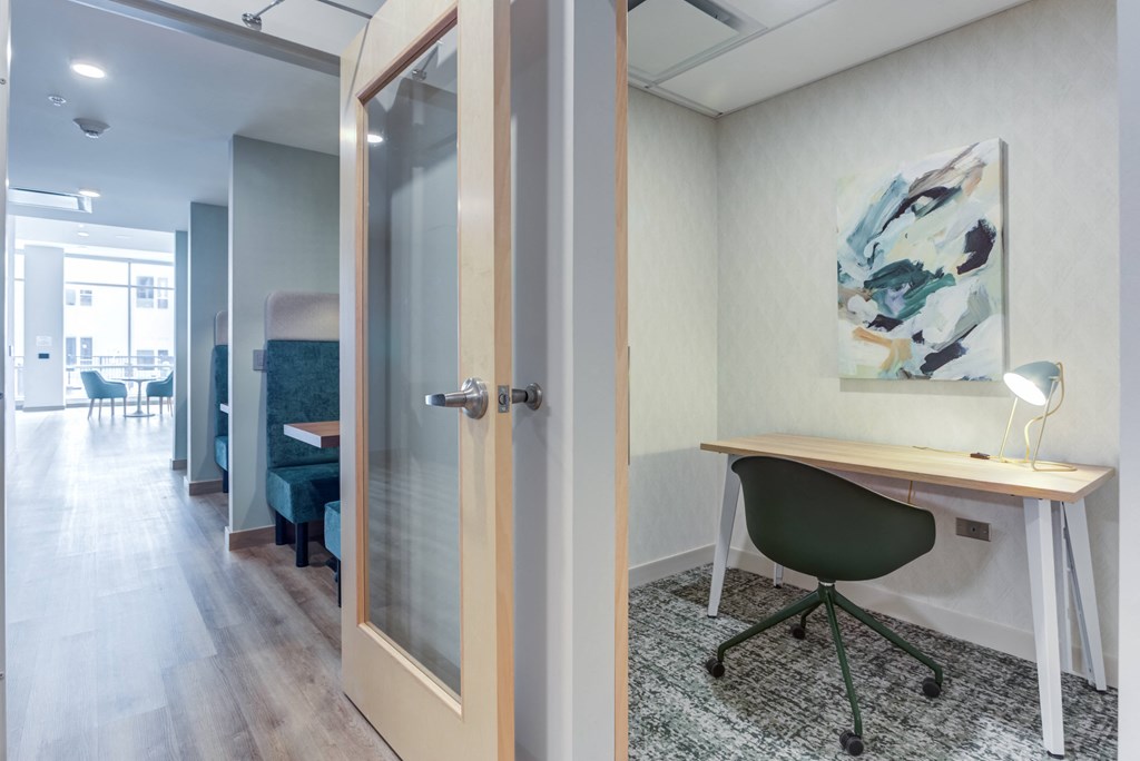 a home office with a desk and a door to a living room