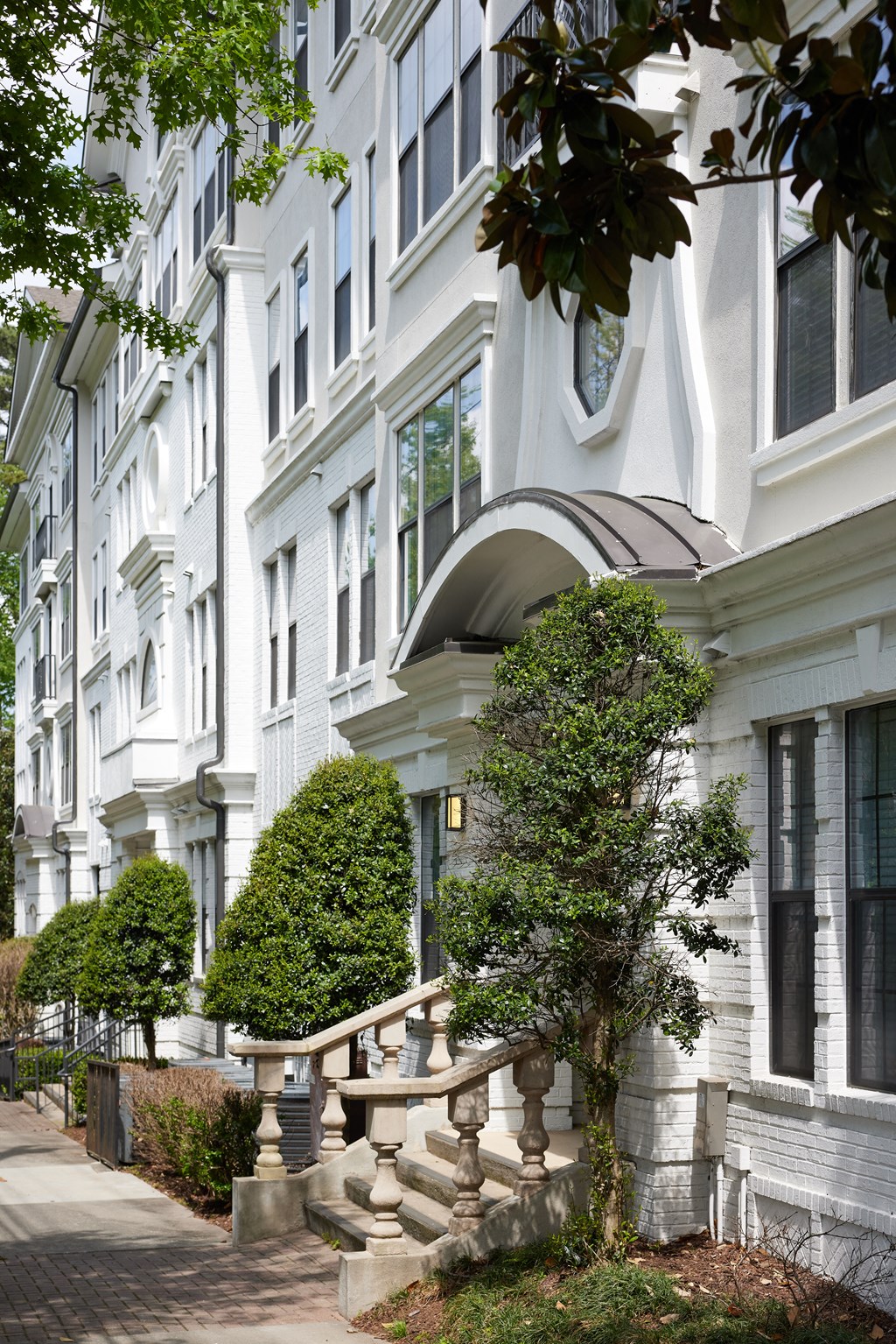 a large white building with a staircase and trees in front of it