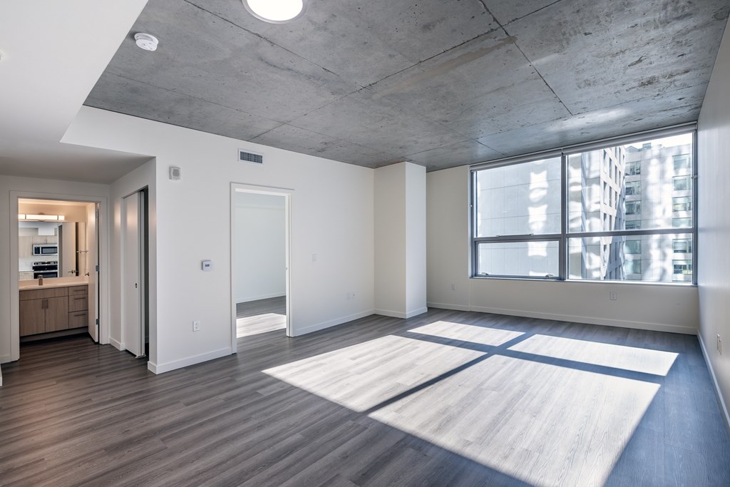 A large open room with a concrete ceiling and a large rug on the floor.