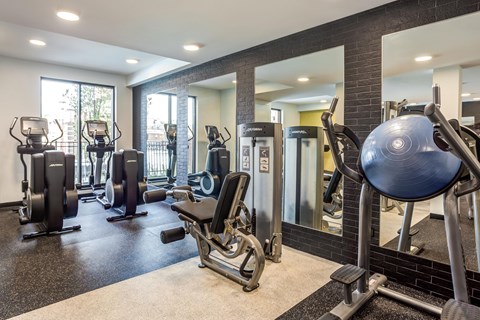 A gym with a variety of equipment including treadmills, weights, and exercise machines.