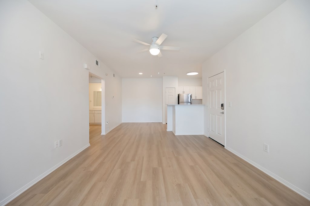 A long, empty room with wooden floors and white walls.