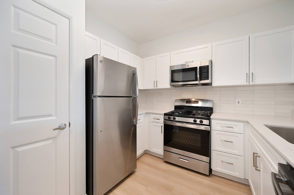 A kitchen with a stainless steel refrigerator, microwave, oven, and stove.