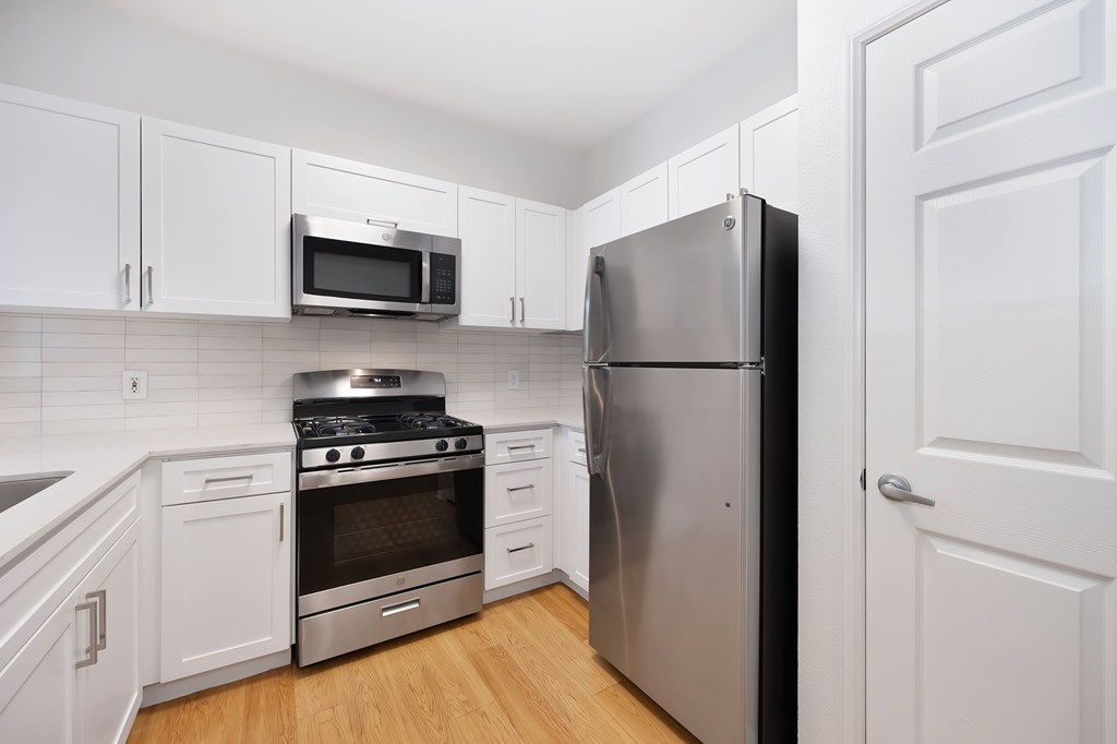 A kitchen with a stainless steel refrigerator, oven, and microwave.