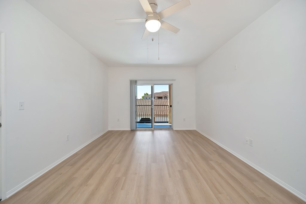 A room with a ceiling fan and wooden flooring.