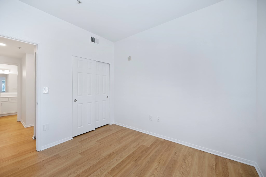 A room with a white door and wooden flooring.