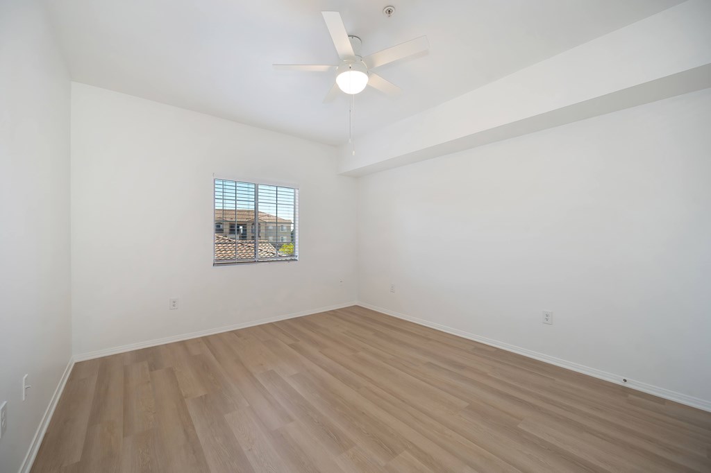 Empty room with wooden floor and ceiling fan.