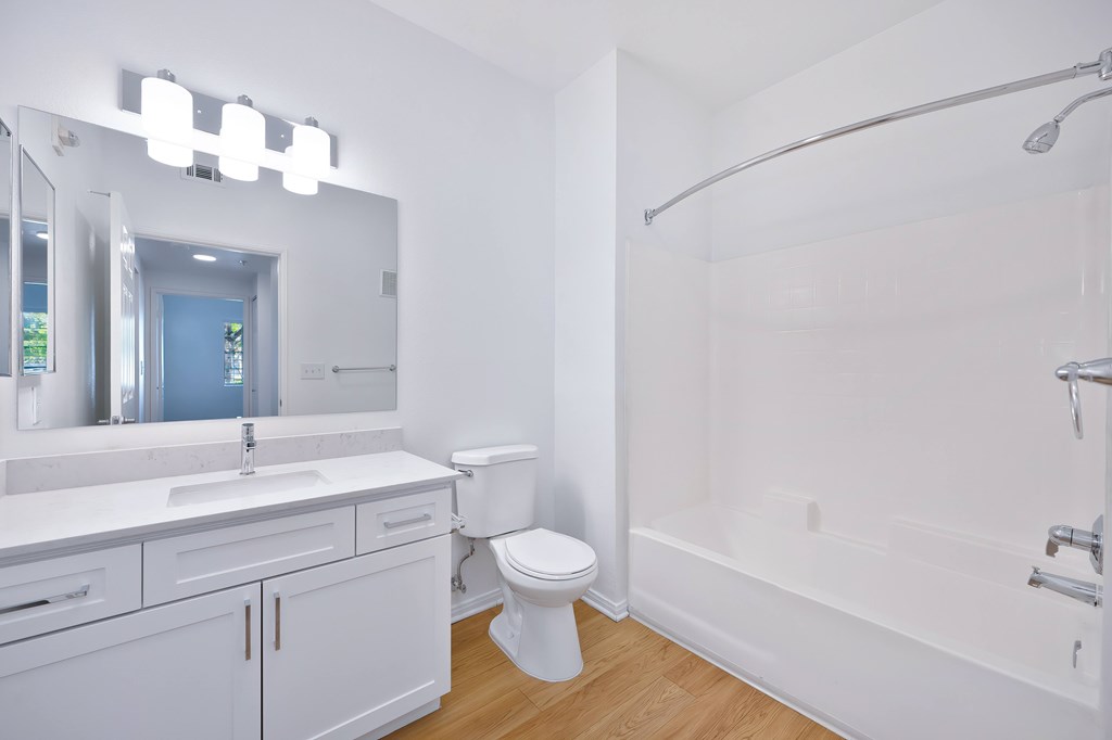 A white bathroom with a toilet, sink, and mirror.
