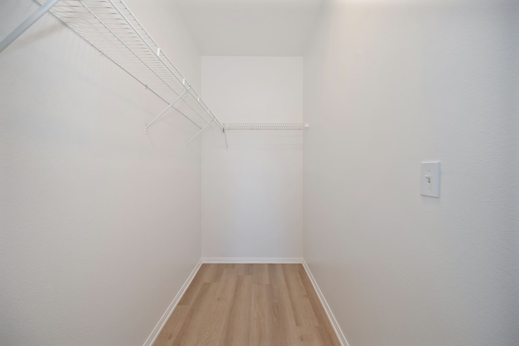 A white wall with a light switch and a white shelf.