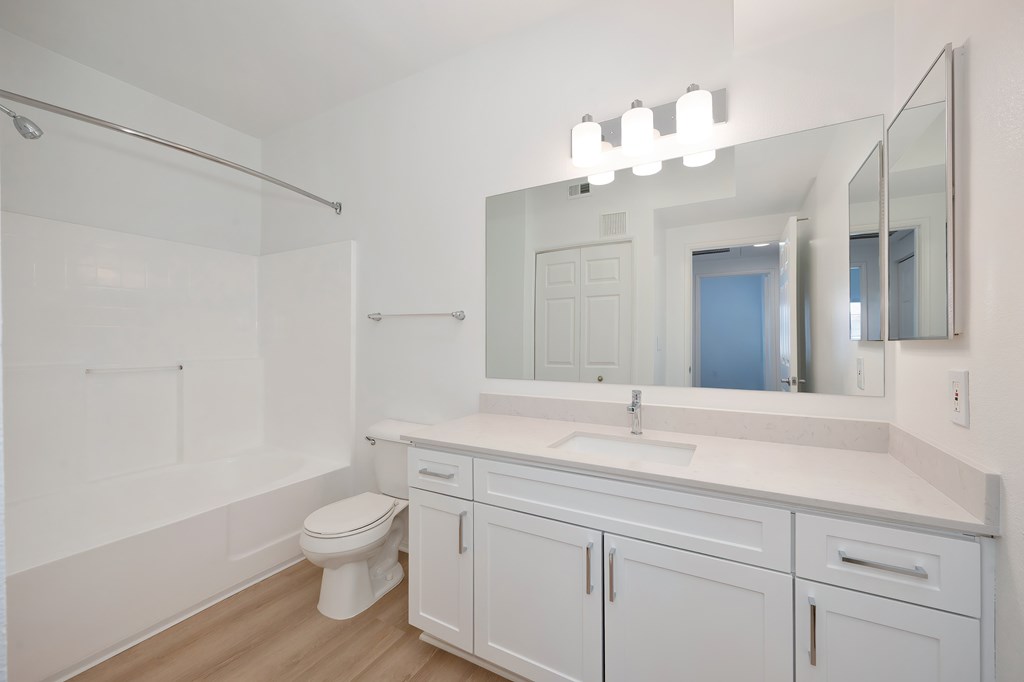 A white bathroom with a toilet, sink, and mirror.