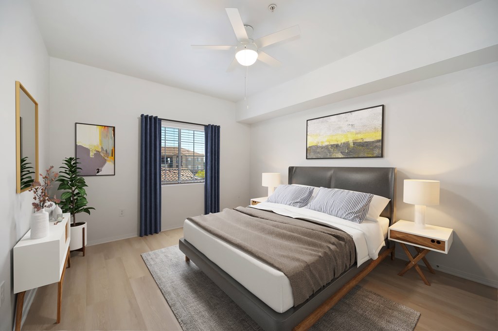 A bedroom with a large bed, a ceiling fan, and a painting on the wall.