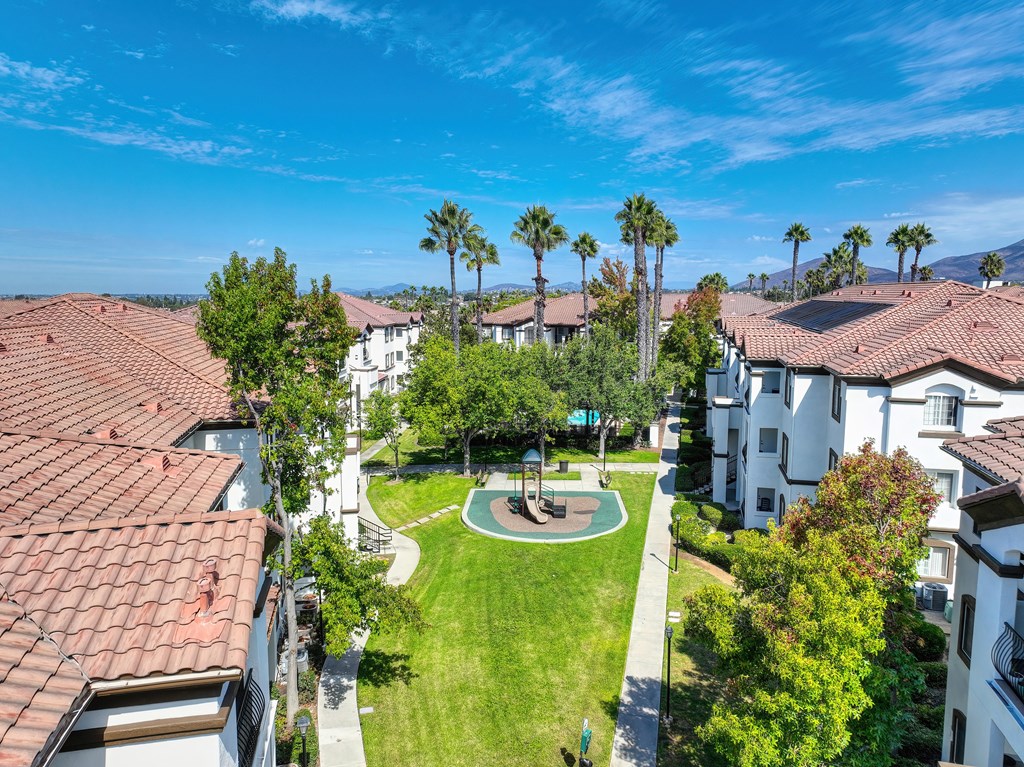 A sunny day at a residential complex with a playground in the middle.