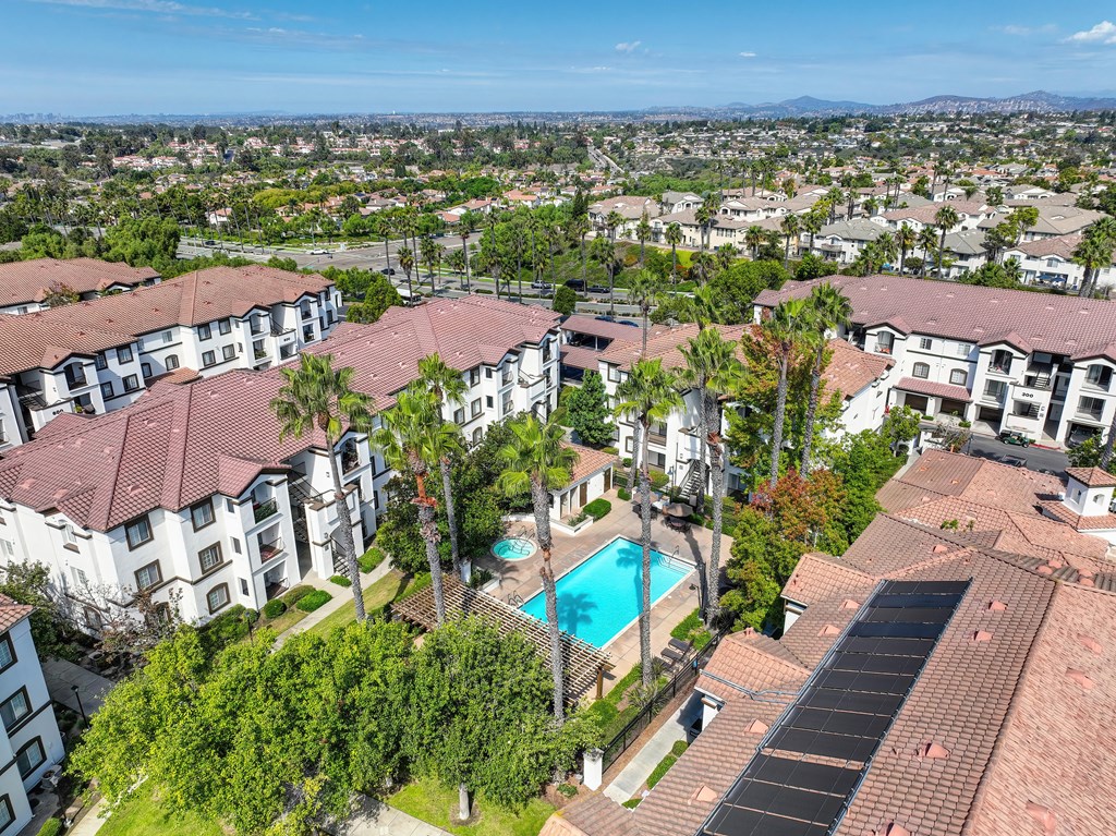 A large apartment complex with a swimming pool and palm trees.