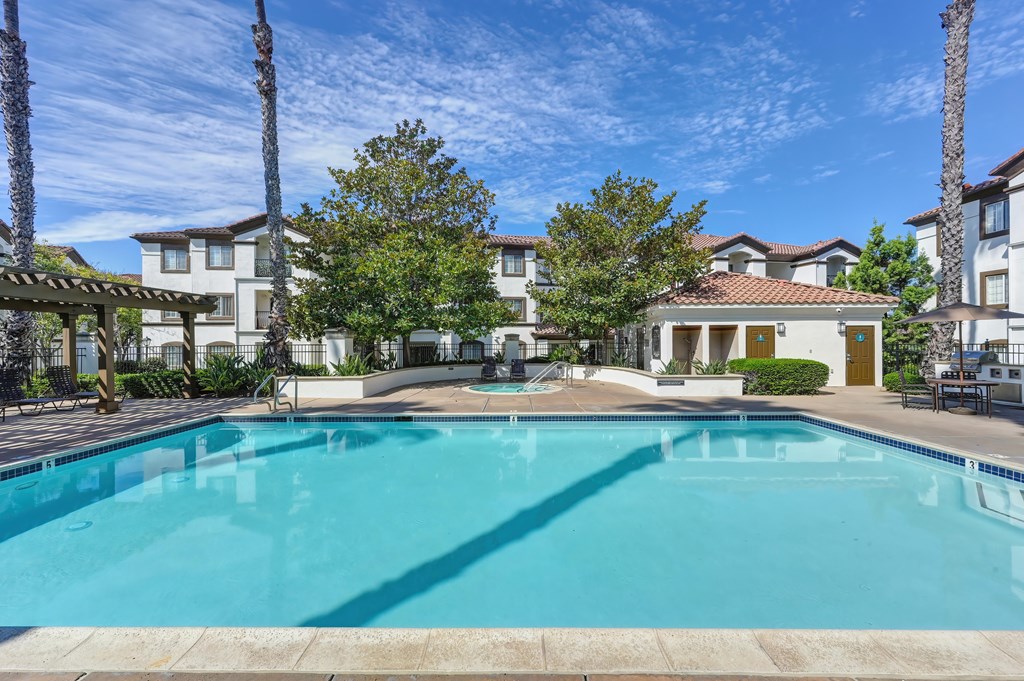 A swimming pool surrounded by palm trees and buildings.