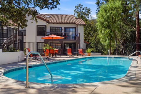 A pool with a slide and a house in the background.