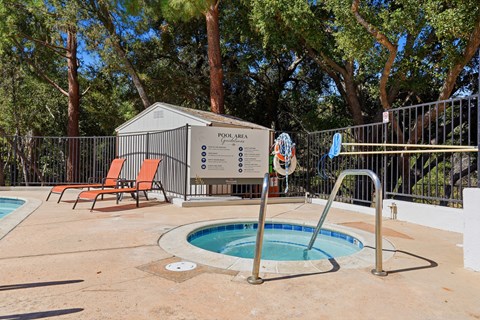 A pool area with a pool, sun loungers and a pool house.