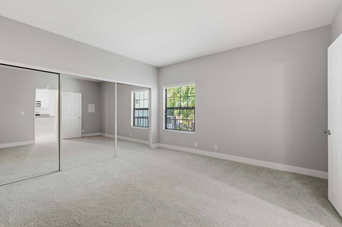 A spacious room with a carpeted floor and a large window.