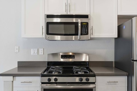 A modern kitchen with a stainless steel stove and microwave above it.