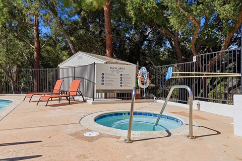 A pool area with a pool, sun loungers and a pool house.