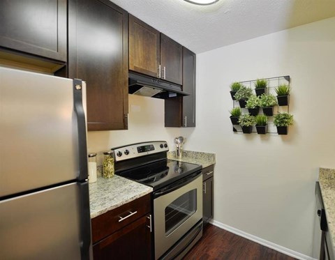 A kitchen with a stainless steel refrigerator, a stove top oven, and a wall-mounted herb garden.