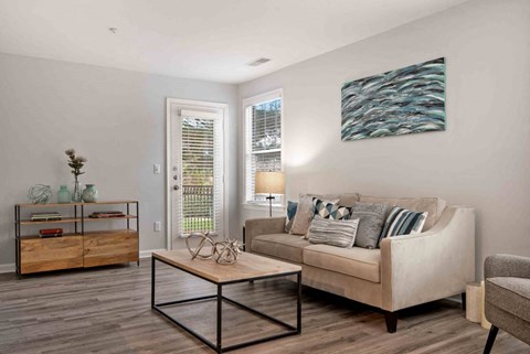 A living room with a couch, coffee table, and a painting on the wall.