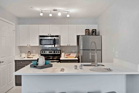 A kitchen with white cabinets and a white island with a sink.