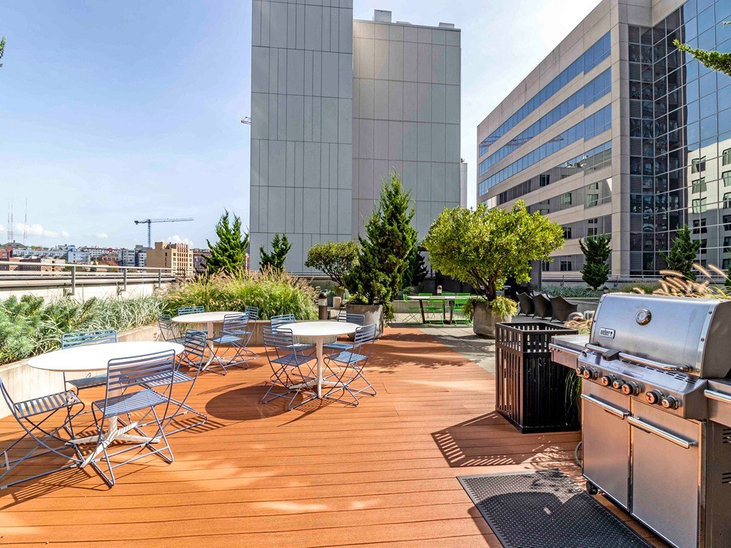a barbecue grill on a rooftop patio with tables and chairs