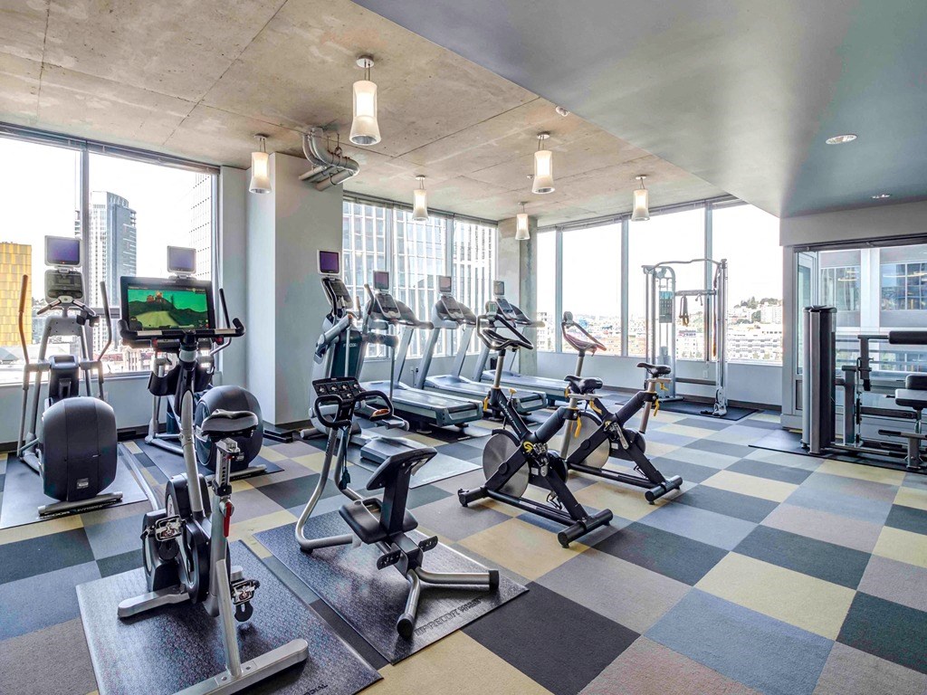 a gym with cardio equipment and a view of the city