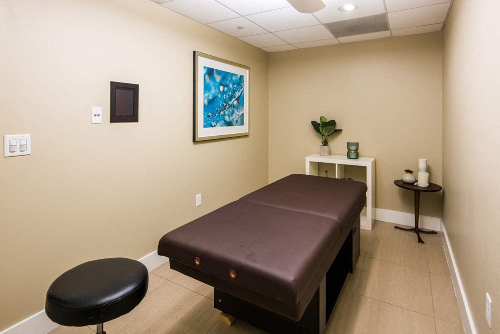 a treatment room with a massage table and a stool