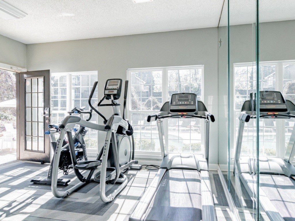 a workout room with treadmills and glass windows