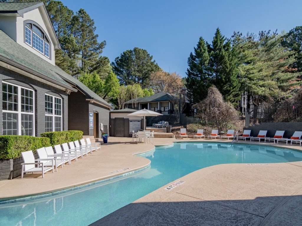 a swimming pool with chairs around it in front of a house