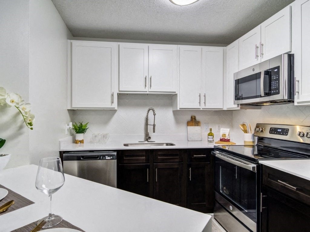 a kitchen with white cabinets and black appliances and a white counter top